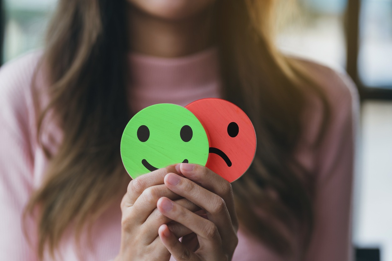 woman holding happy face with a sad face behind