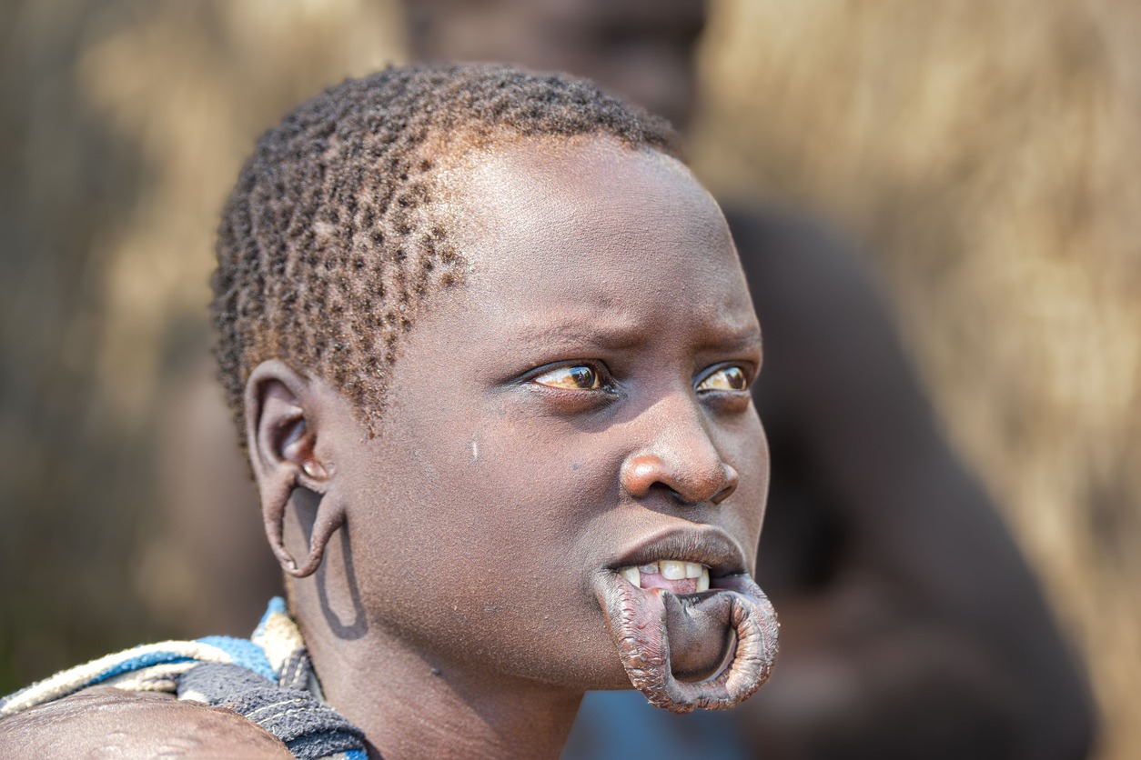 young African male with traditional body modifications including ear lobe stretching from the Mursi Tribe