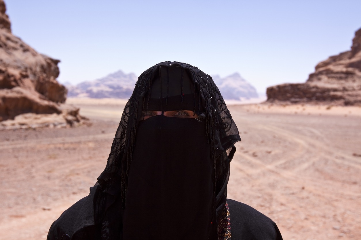 Bedouin woman dressed in Traditional burka standing alone in the desert