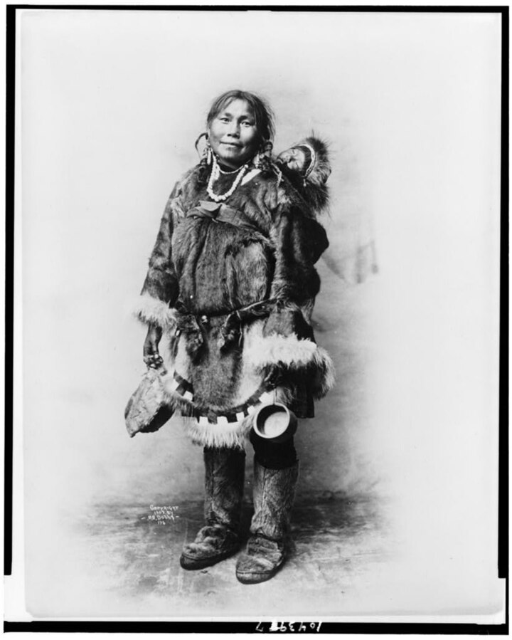 Eskimo mother dressed in fur clothing with baby on her back
