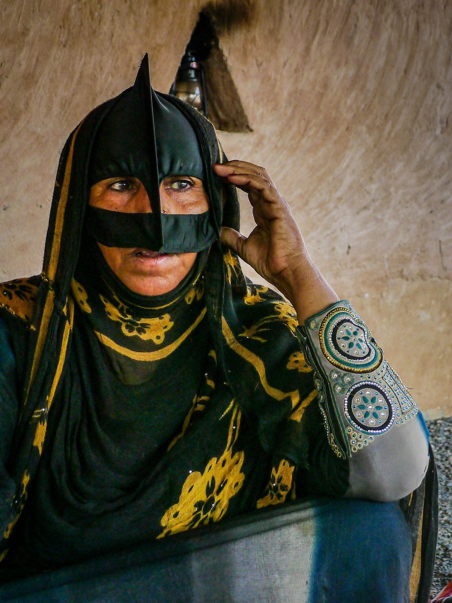 Omani Bedouin woman wears a traditional batoola face covering in the Wahiba Sands desert of Oman