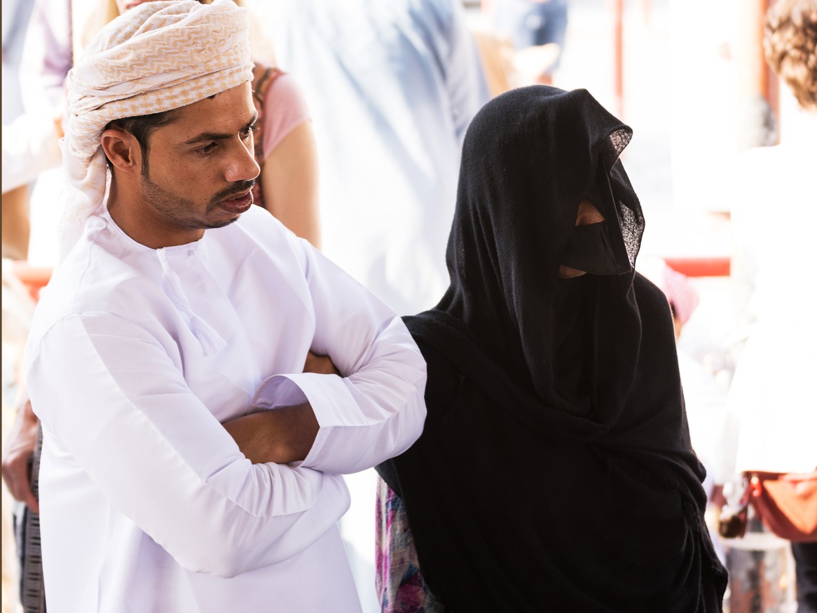 Omani couple in traditional clothes with a woman wearing a veil and a mask