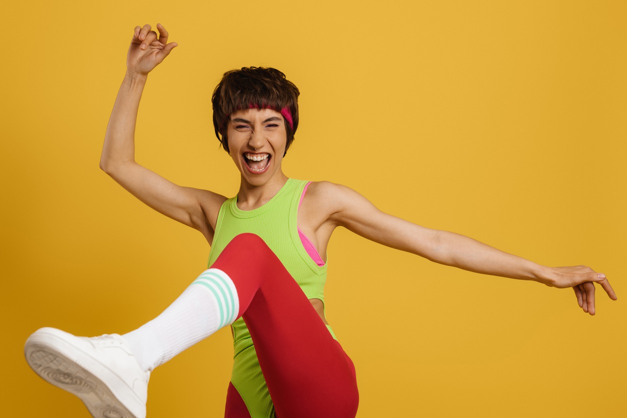 excited fit woman in retro styled sports clothing dancing