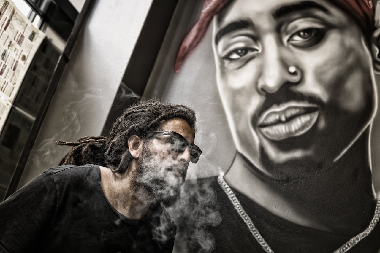man posing with portrait of Tupac Shakur