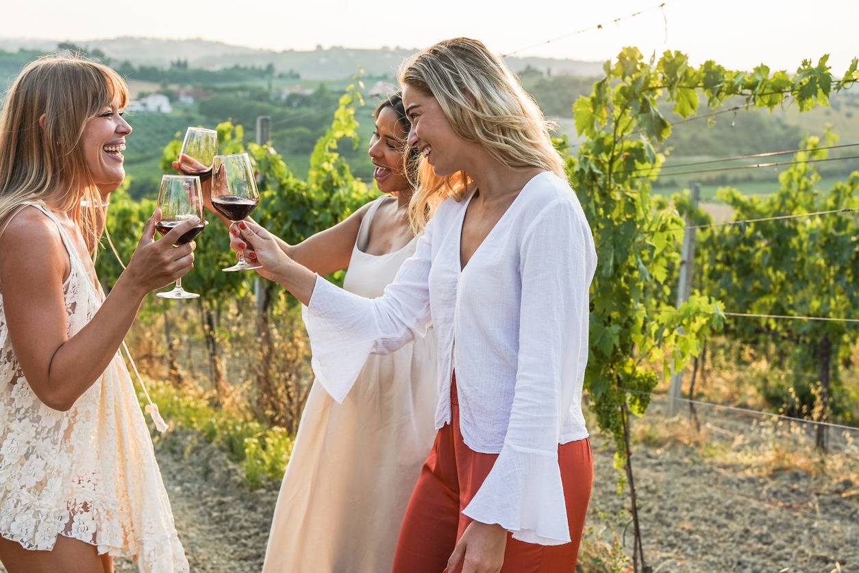 three women tasting wine in a vineyard