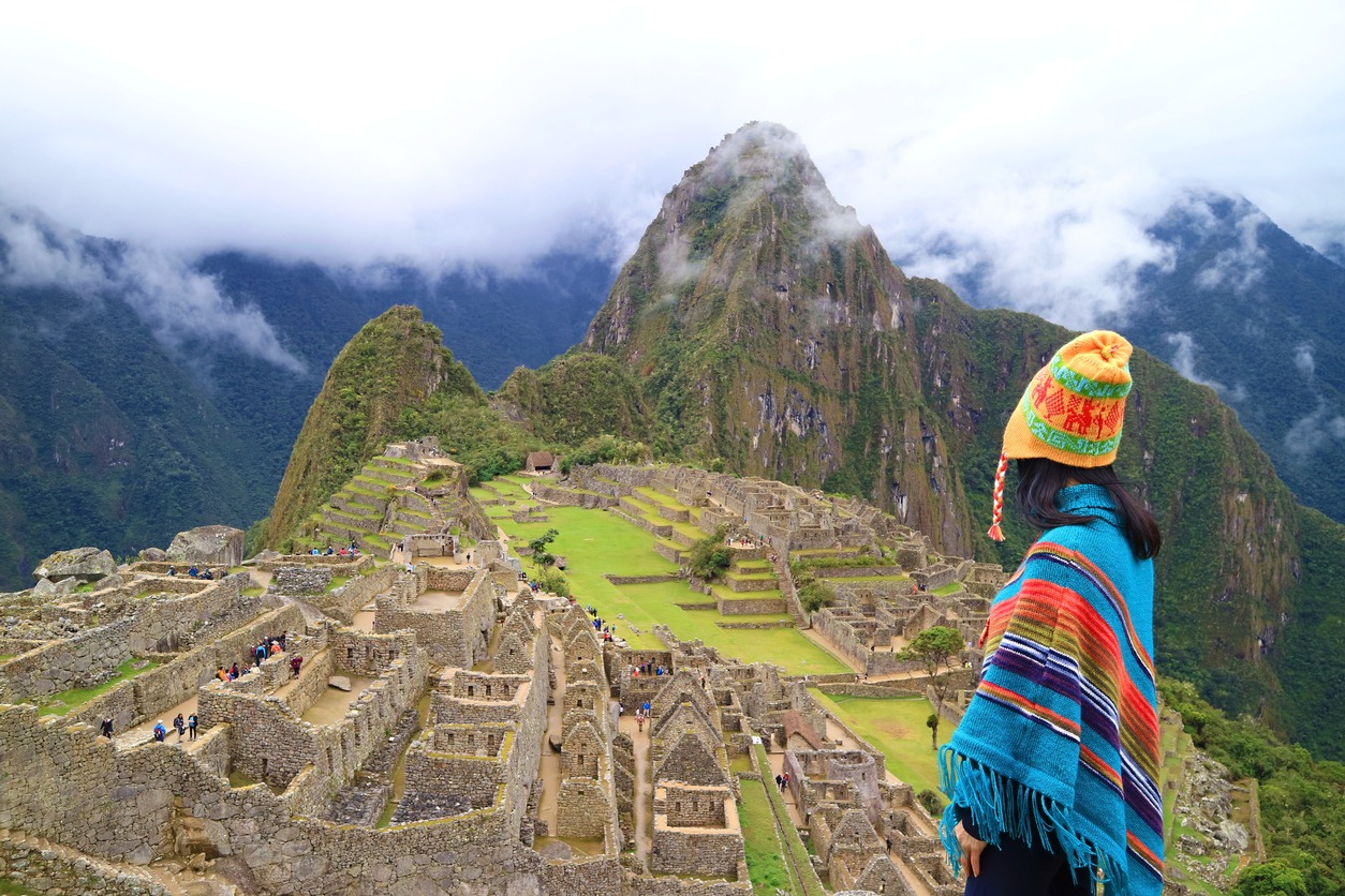 woman wearing a chullo hat admiring the Ancient Inca Citadel of Machu Picchu