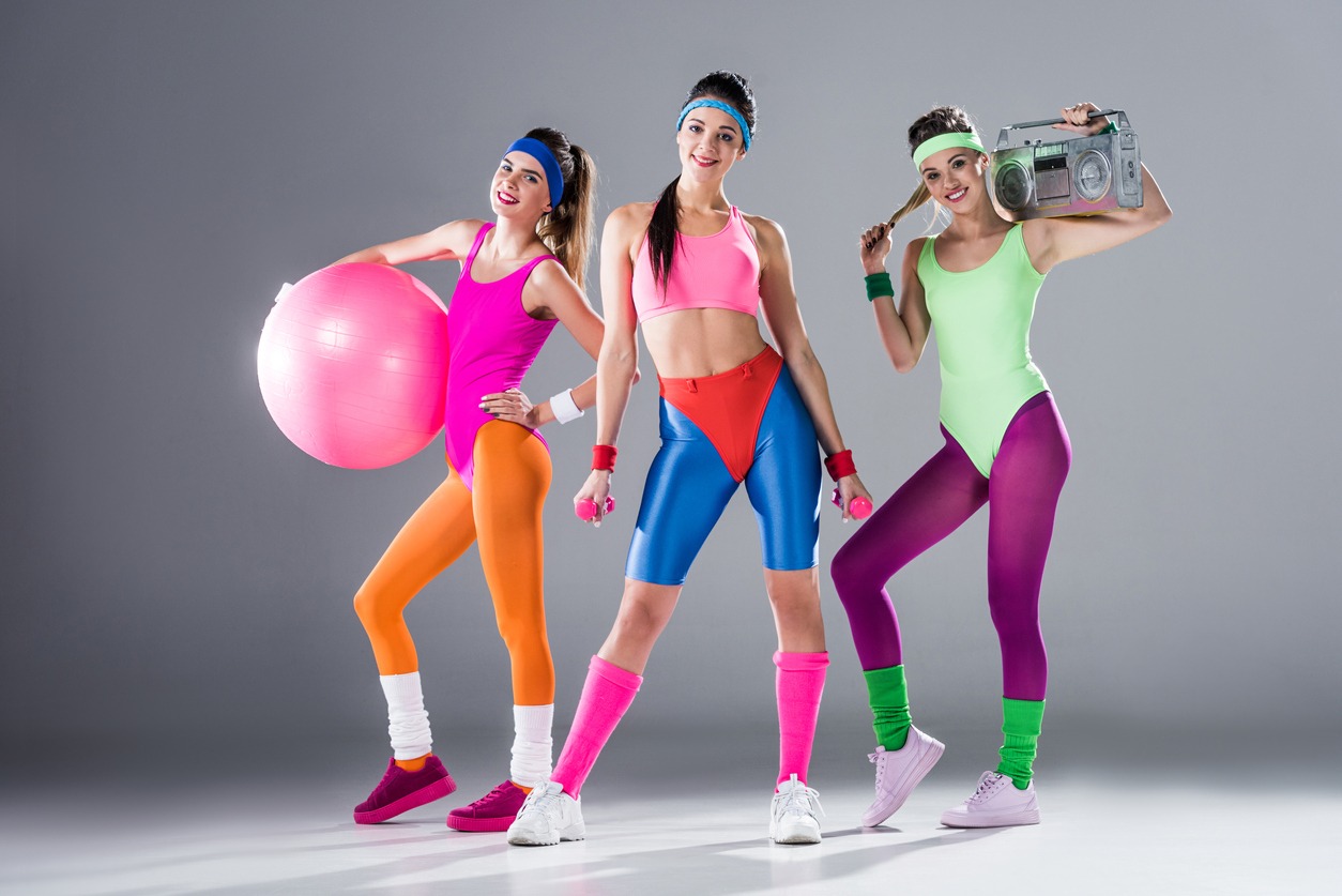 women wearing 80s inspired fitness outfits with sports equipment and tape recorder