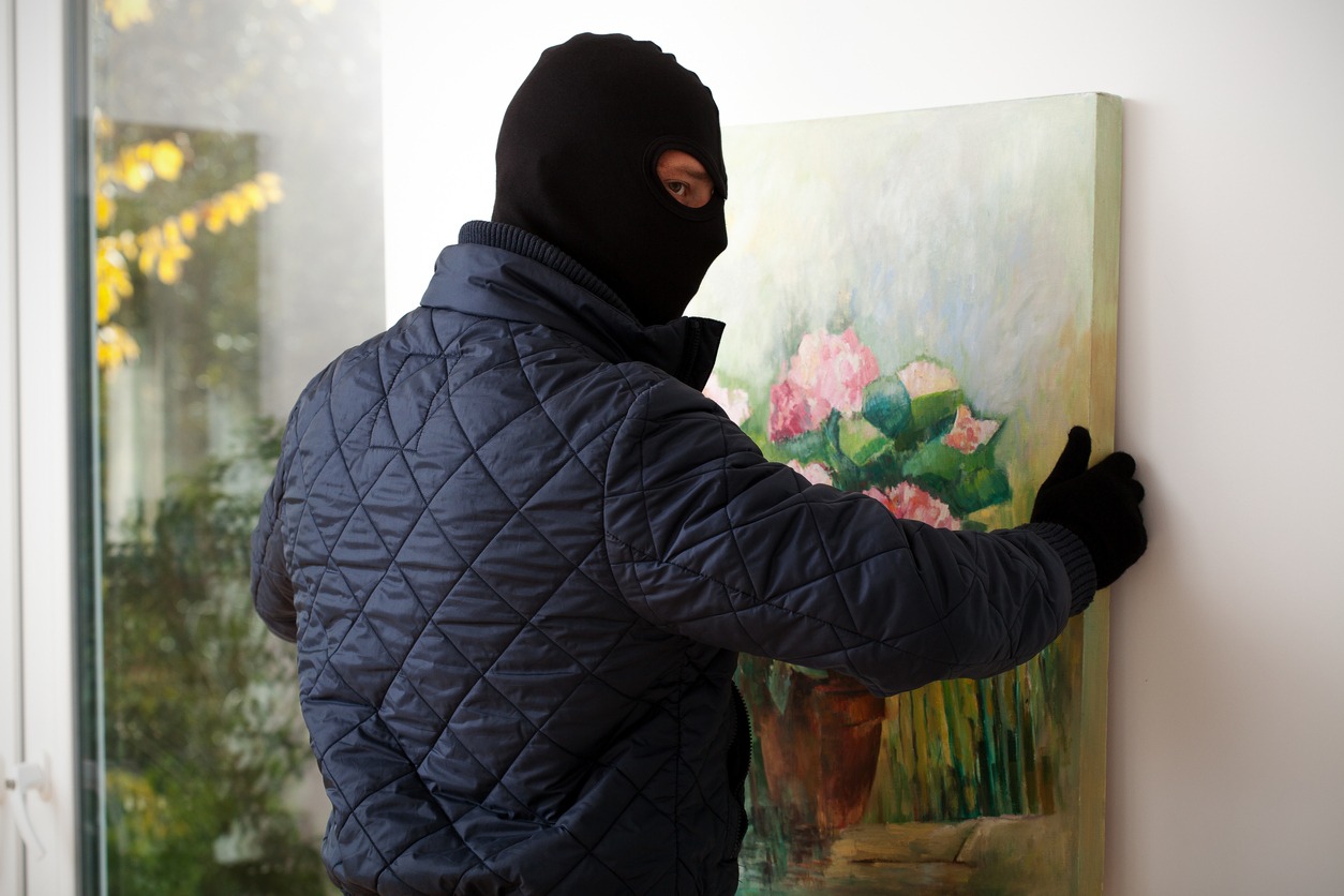 masked man stealing a painting
