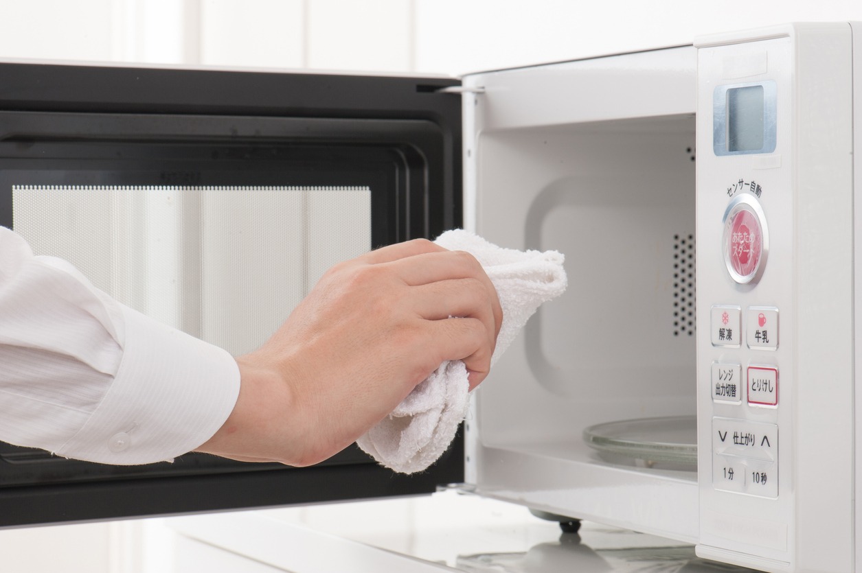 person cleaning a microwave