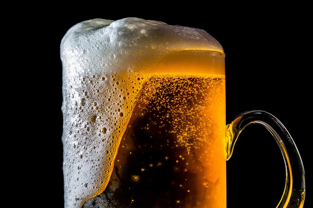 A glass of beer with overflowing foam