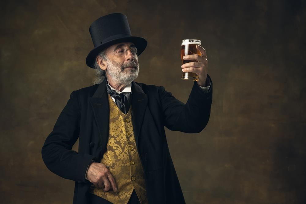 Elderly gray-haired man holding a glass of beer