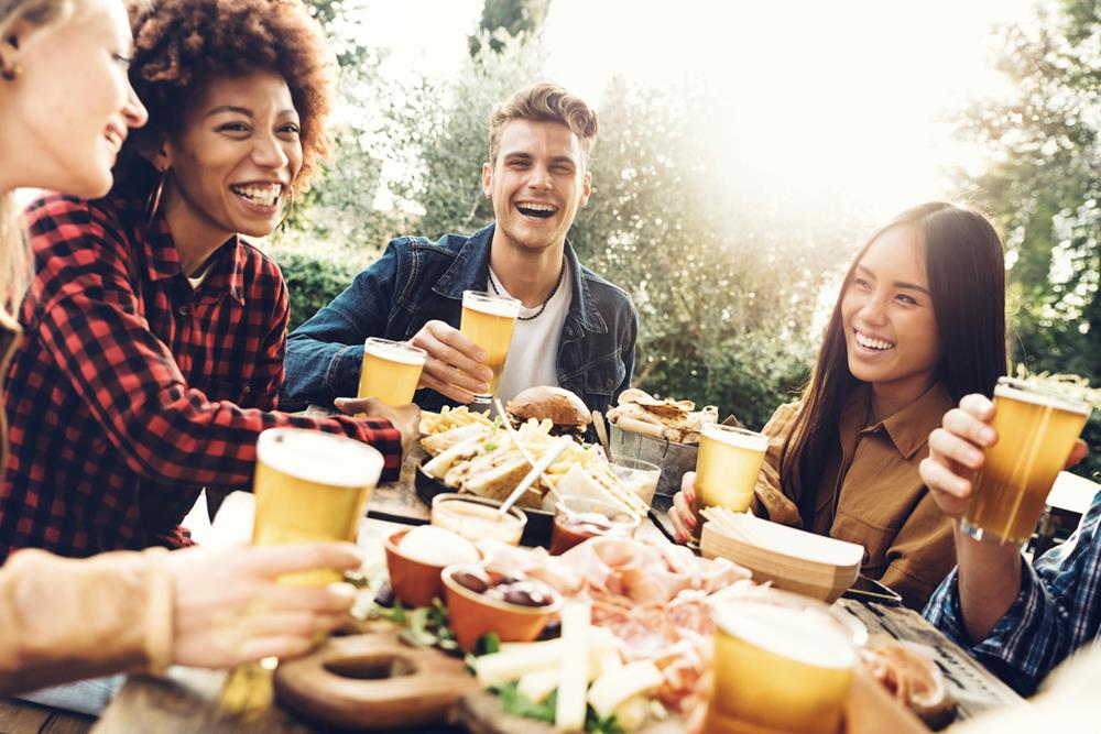 Group of multi-ethnic people having backyard dinner and enjoying beer together