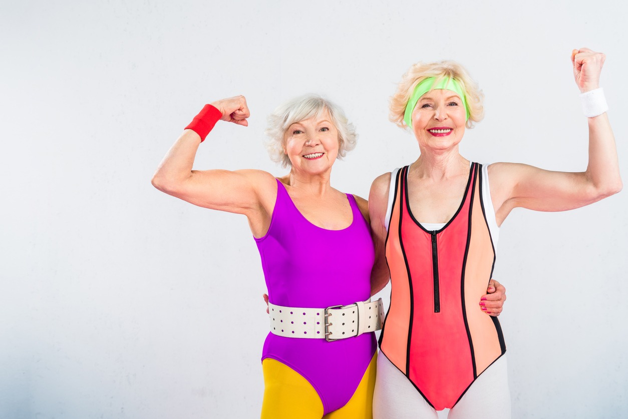 happy senior sportswomen showing muscles and smiling