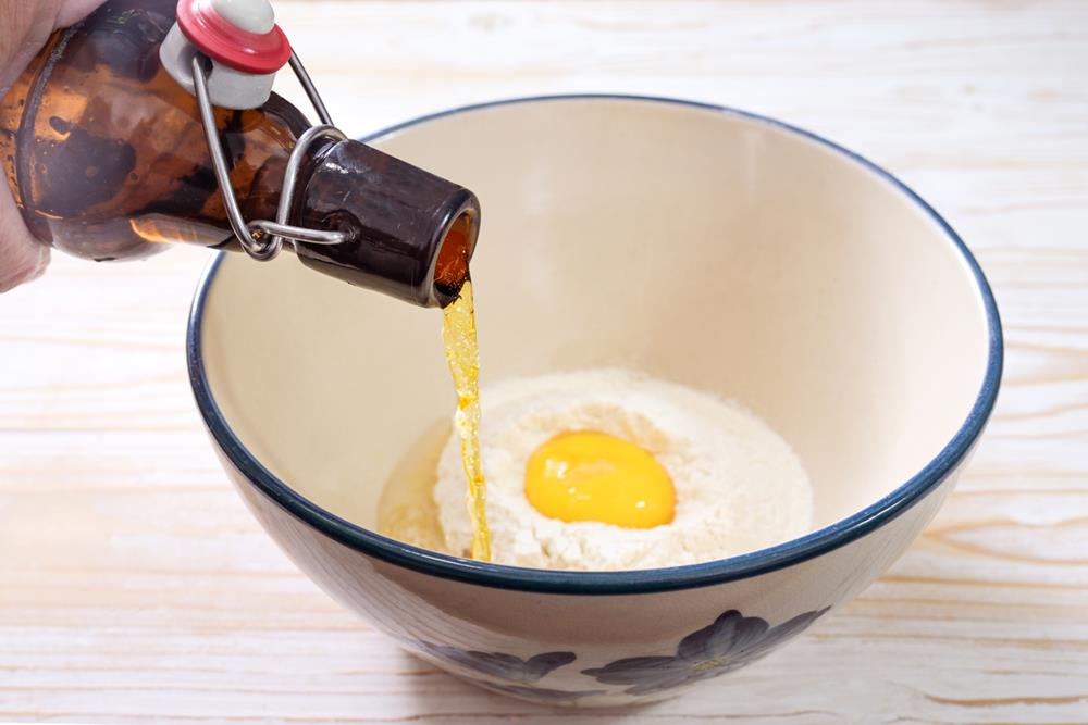 Pouring beer in a bowl with egg and flour